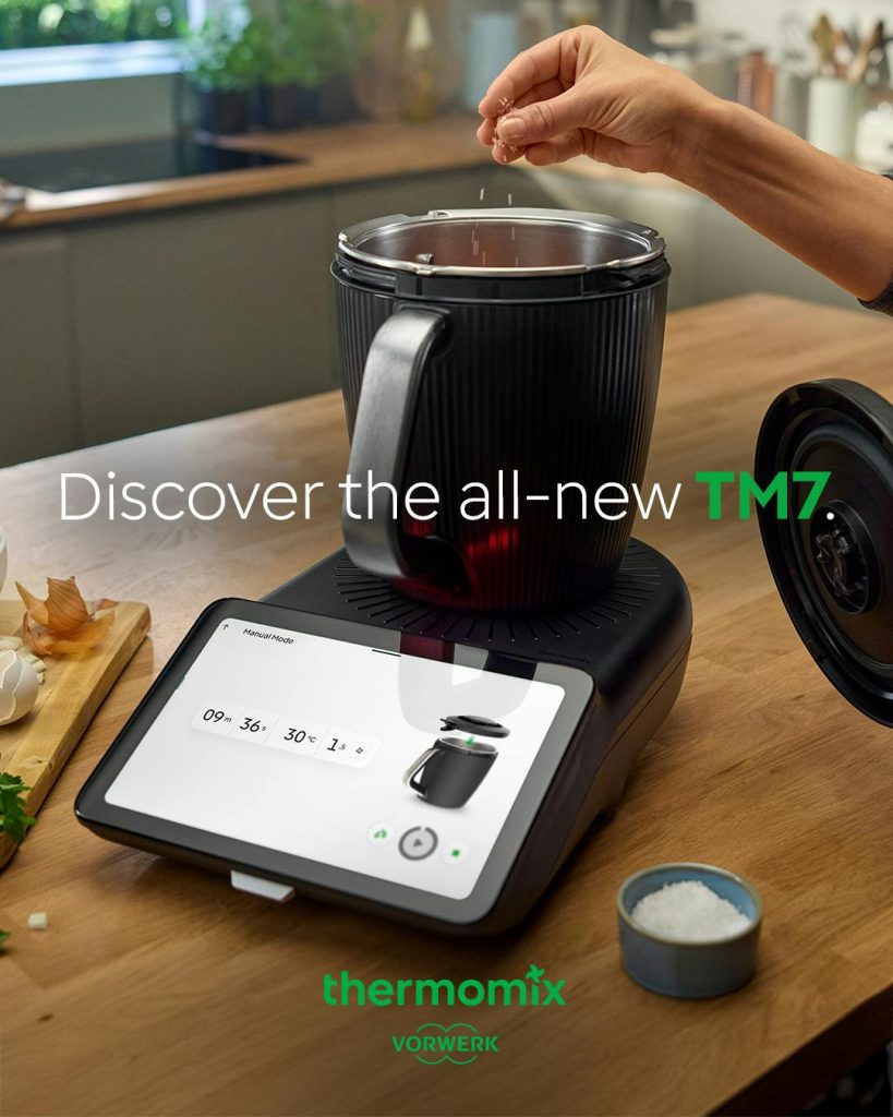 Thermomomix TM7 on a worktop - showing someone putting ingredients in